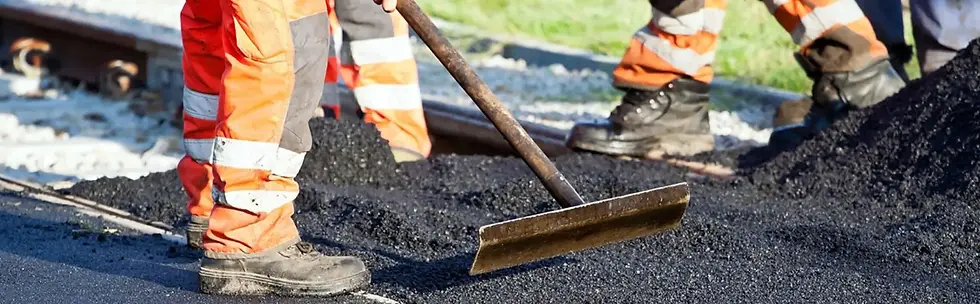 Close up of construction workers in high visibility uniform raking and smoothing ground aggregate foundations