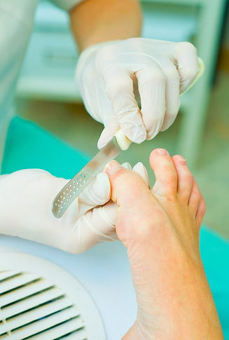 A gloved professional performs a pedicure