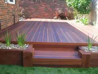 Wooden deck with smooth planks and integrated planters filled with pebbles and greenery