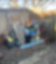 A cluttered backyard filled with various junk items, enclosed by a wooden fence