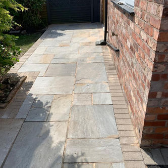 Natural stone patio alongside brick house wall