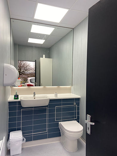 Accessible bathroom with a modern design featuring a wall-mounted sink, toilet, and safety grab bars