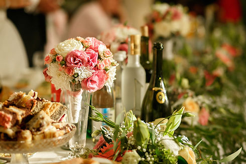 Wedding reception table set with floral centerpiece, wine bottles and dessert platter
