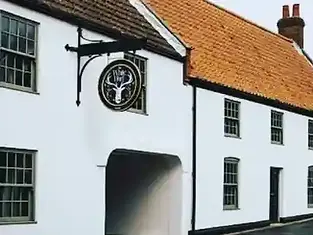 Exterior of The White Hart pub featuring a black stag sign and orange tiled roof on a white building