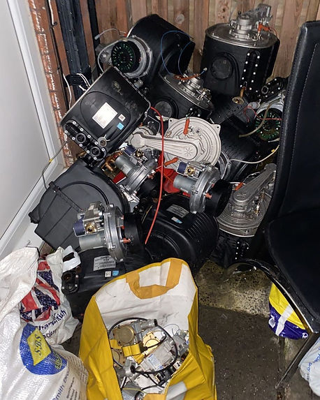 A cluttered pile of various electronic and mechanical parts is stacked in a corner