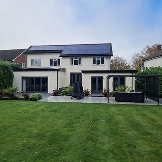 Large white modern house with a dark roof and a spacious manicured green lawn under a blue sky