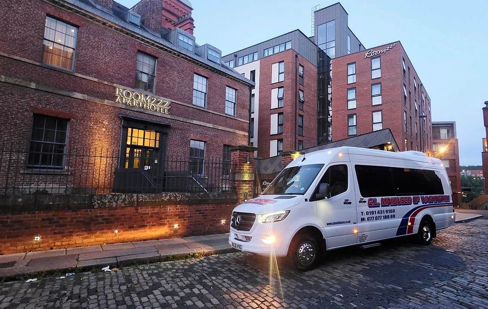 White minibus parked on a cobbled street outside a brick building at dusk