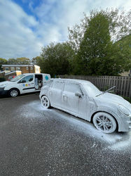 White Tesla Model Y covered in snow foam during exterior wash