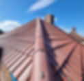 A red tiled gable roof under a clear blue sky