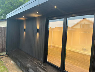 Modern black garden room with recessed lighting, large glass sliding