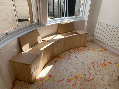 Curved wooden bench with backrest under bay window