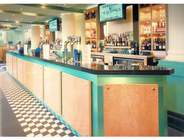 A retro-style bar with teal and wood decor, checkered floor, and vintage elements