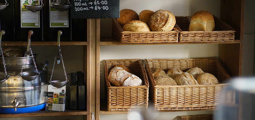 Freshly baked artisanal bread loaves on rustic wooden display shelves in a warm bakery