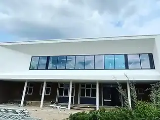 Modern white building with large black-framed glass windows and architectural support pillars