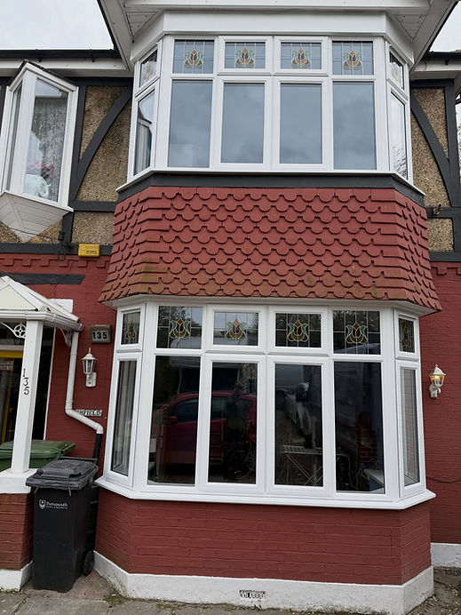 Large white double glazed bay windows on the upper floor of a brick residential home