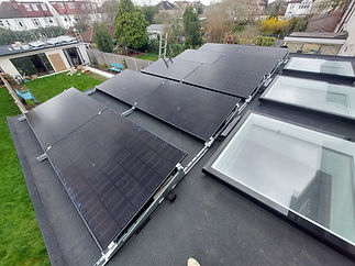 A flat rooftop with several large solar panels mounted next to three skylights