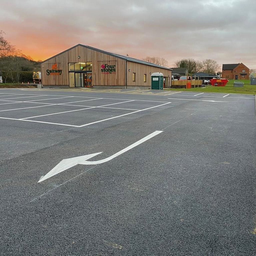 Painted white arrows directing traffic flow on a newly surfaced commercial car park layout