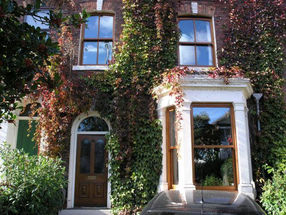 Featuring two tall rectangular windows and a wooden door