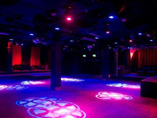 Empty nightclub dancefloor illuminated with pink and blue laser