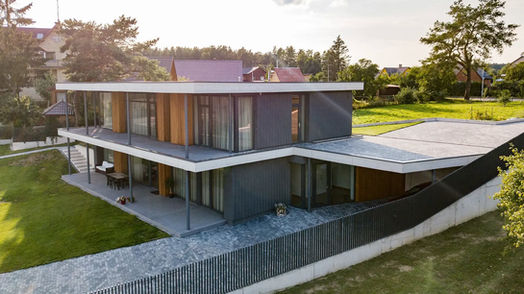 Aerial view of modern two-storey architectural house with flat roof, glass walls and surrounding garden