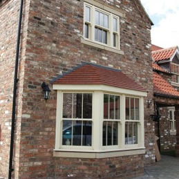 A rustic brick house with a prominent bay window framed