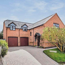 A two-story brick house with a gabled roof, double garage, and a paved driveway