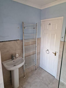 Bathroom with light blue walls, beige tile halfway up.