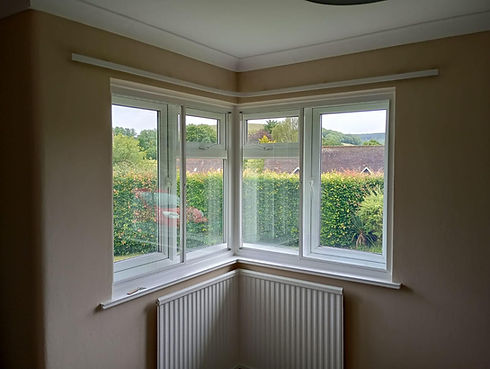 White uPVC corner windows with a scenic green garden view in a light-coloured room