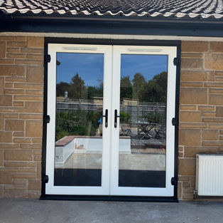 White double glazed patio doors set into a light brown stone brick wall