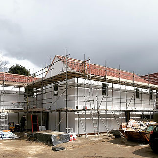 A partially constructed building with scaffolding surrounds white walls 