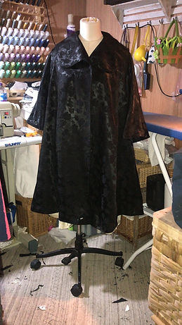 Blurred silhouette of a person wearing a long black garment in a colorful indoor setting