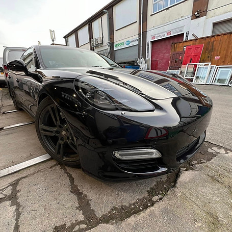 Glossy black Porsche Panamera parked in front of Bespoke and MBS Windows warehouse