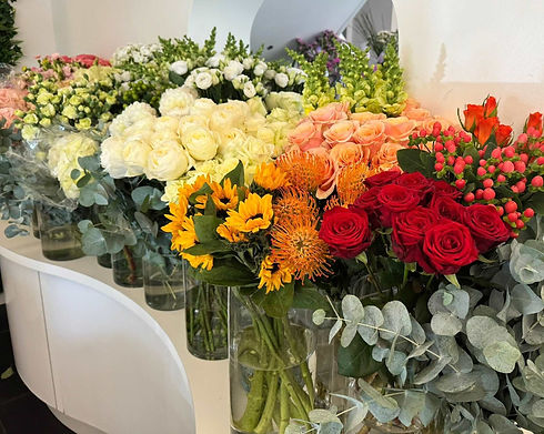 Rows of diverse freshly prepared flower bouquets arranged on a countertop in a bright florist shop