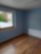 Empty room with light blue walls and wood effect flooring featuring a white radiator and window