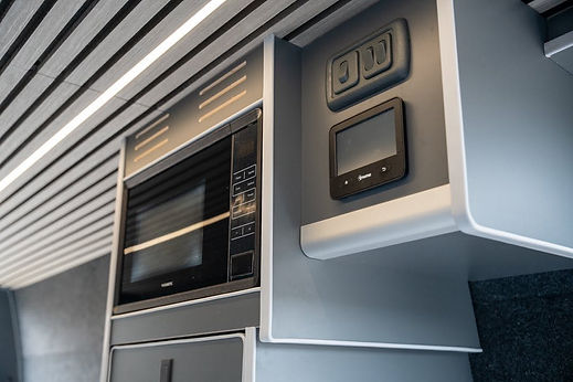 Close up of a fitted grey van conversion cabinet featuring a built-in microwave and electronic control panel