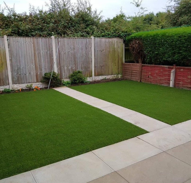 A neatly maintained backyard with lush green grass, a stone pathway