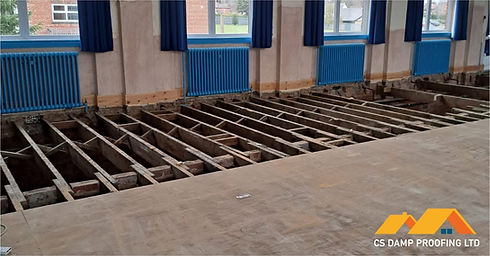 Large room renovation showing exposed timber floor joists after removing old floorboards