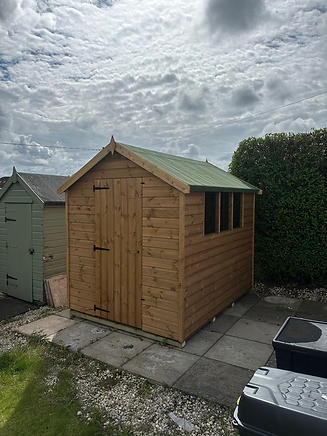 Wooden garden shed with a green roof on a paved area