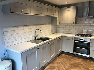 Modern kitchen with gray cabinets, white subway tile backsplash, and chevron wood flooring