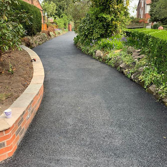 Curved tarmac pathway through landscaped garden