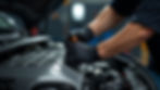 Mechanic's gloved hands working on a car engine, adjusting a component