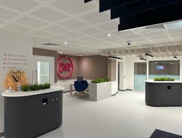 Modern office interior with sleek black desks, plants, and a prominent red logo on the wall