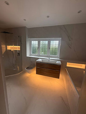 Modern bathroom with marble tiles, featuring a walk-in shower, floating vanity