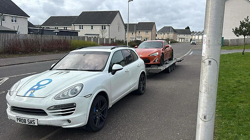 White Porsche Macan parked on a residential street with a red car behind it