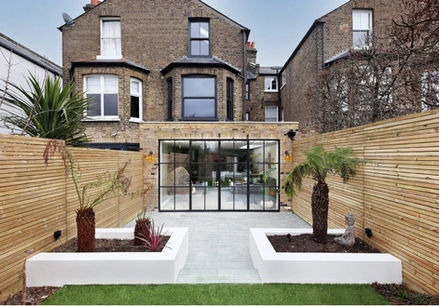 Modern backyard with a wooden fence, two white planter boxes with palm trees