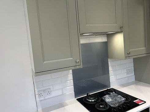 Modern grey shaker style kitchen cabinets with white countertop and black stovetop