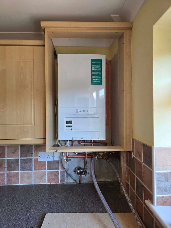 Gas boiler installed in a kitchen alcove, surrounded by light wood cabinets