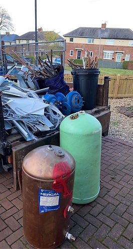 A trailer filled with assorted scrap metal items, a green tank