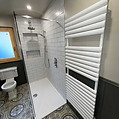 Modern bathroom with white tiles and large walk-in shower featuring glass panels
