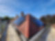 Red-tiled roof with several solar panels under a clear blue sky